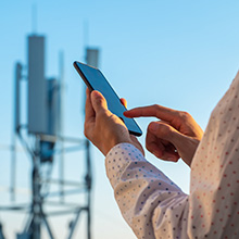 Person holding phone in front of 5G tower